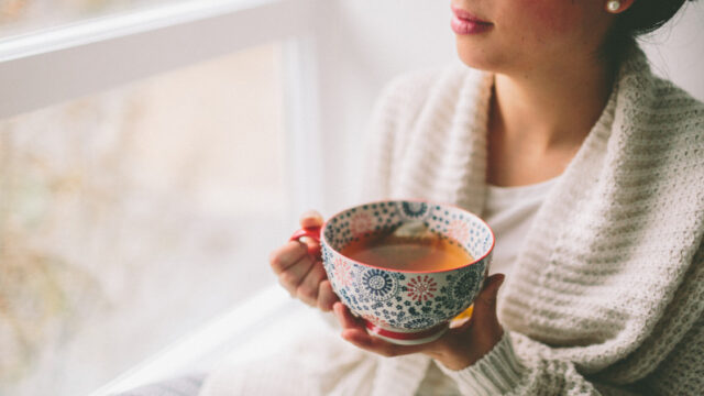 窓辺でお茶を飲む女性の写真