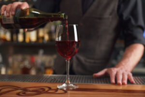 グラスに赤ワインを注ぐバーテンダーの写真